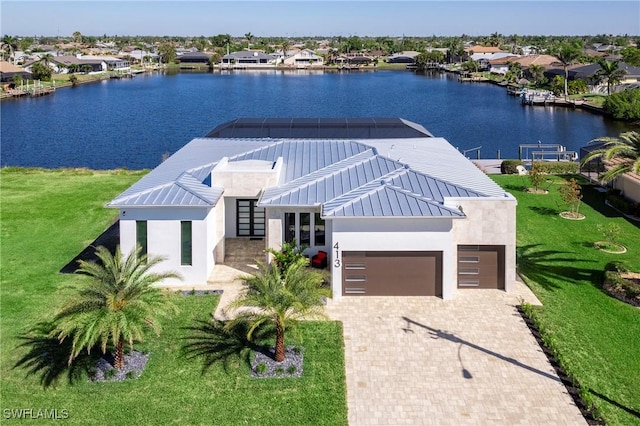 view of front facade featuring a water view, a residential view, stucco siding, decorative driveway, and a garage