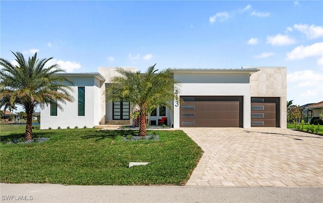 contemporary home featuring a front yard, a garage, driveway, and stucco siding