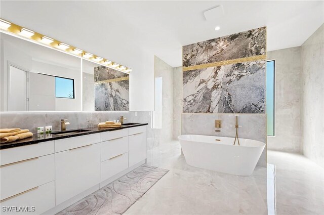 413 SW 46th Ter, Cape Coral, FL 33914 - bathroom featuring double vanity, a freestanding tub, marble finish floor, tile walls, and a sink