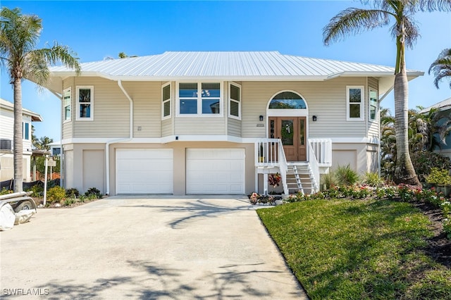 view of front of property featuring metal roof, driveway, a front yard, and an attached garage