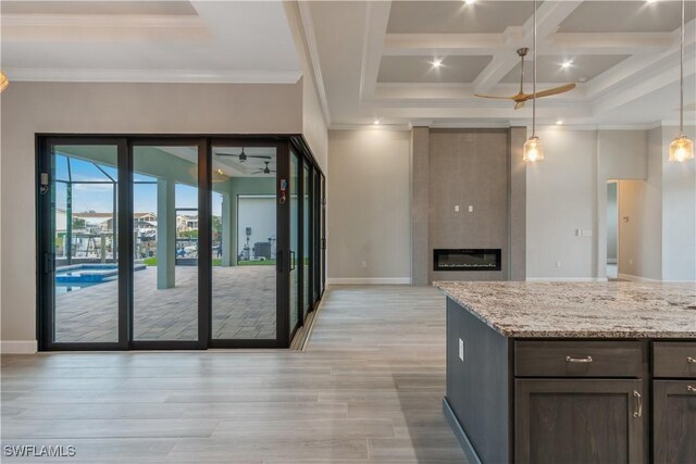 4320 Vasco St, Punta Gorda, FL 33950 - kitchen featuring a large fireplace, light stone counters, decorative light fixtures, crown molding, and light wood-style floors