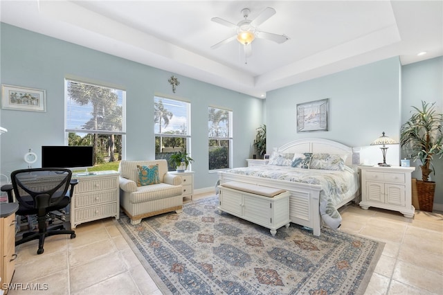 bedroom featuring light tile patterned floors, baseboards, a raised ceiling, and a ceiling fan