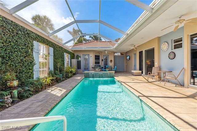 outdoor pool with glass enclosure, a patio area, and a ceiling fan