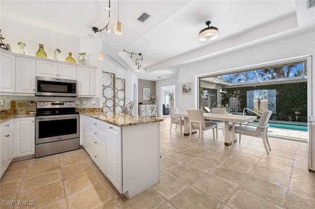 kitchen with visible vents, decorative backsplash, appliances with stainless steel finishes, white cabinetry, and a peninsula