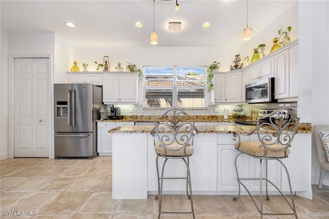 kitchen featuring light stone counters, stainless steel appliances, backsplash, white cabinetry, and a peninsula