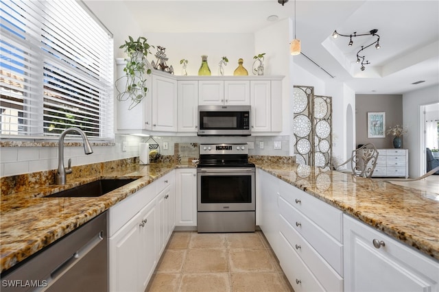 kitchen with tasteful backsplash, white cabinets, a tray ceiling, stainless steel appliances, and a sink