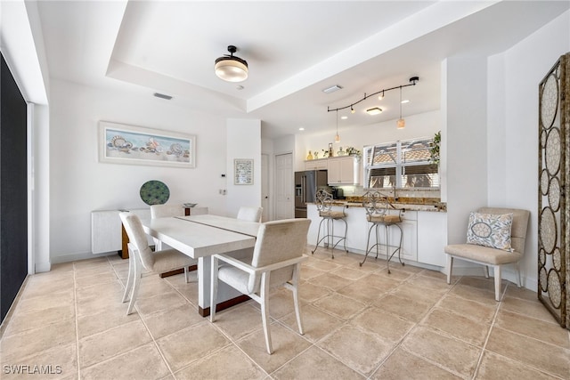 dining space with light tile patterned floors, baseboards, visible vents, and a raised ceiling