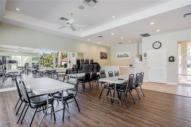 dining area featuring light wood finished floors, visible vents, a raised ceiling, and recessed lighting