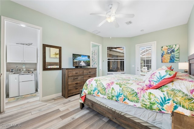 bedroom featuring light wood finished floors, visible vents, baseboards, access to outside, and a sink