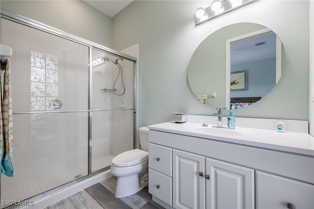 bathroom featuring toilet, a shower stall, wood finished floors, and vanity