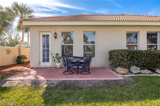 rear view of property featuring a patio area, fence, and stucco siding