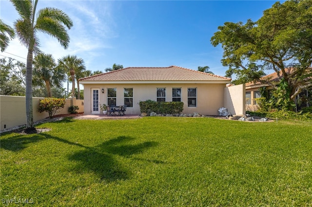 rear view of house featuring a tile roof, fence, a yard, a patio area, and stucco siding