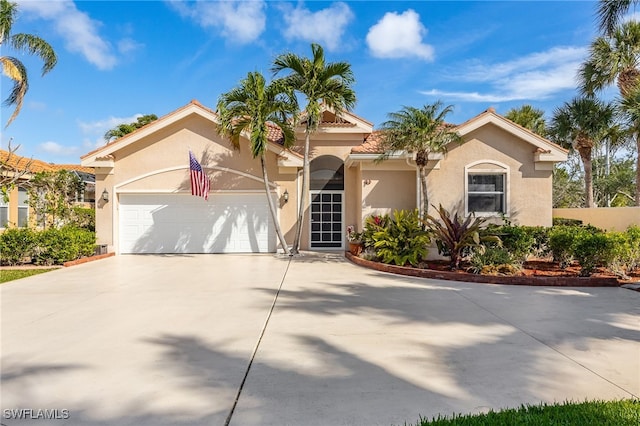 mediterranean / spanish home with a garage, driveway, a tiled roof, and stucco siding