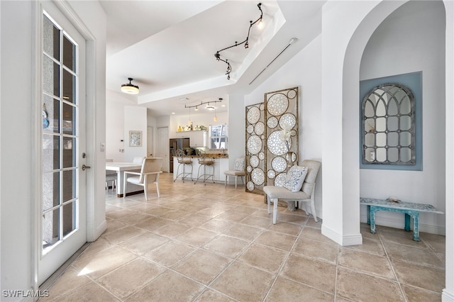 hallway featuring baseboards, light tile patterned flooring, and track lighting