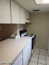 kitchen featuring electric stove, white cabinetry, and light tile patterned floors