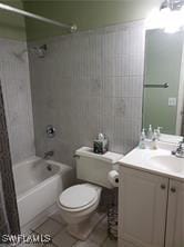 full bathroom featuring tiled shower / bath, vanity, toilet, and tile patterned floors