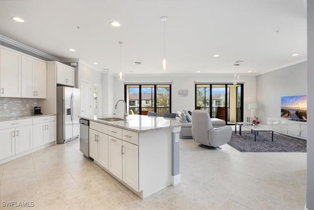 kitchen with tasteful backsplash, appliances with stainless steel finishes, open floor plan, ornamental molding, and a sink