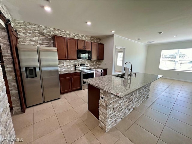 kitchen with light tile patterned flooring, sink, ornamental molding, an island with sink, and stainless steel appliances