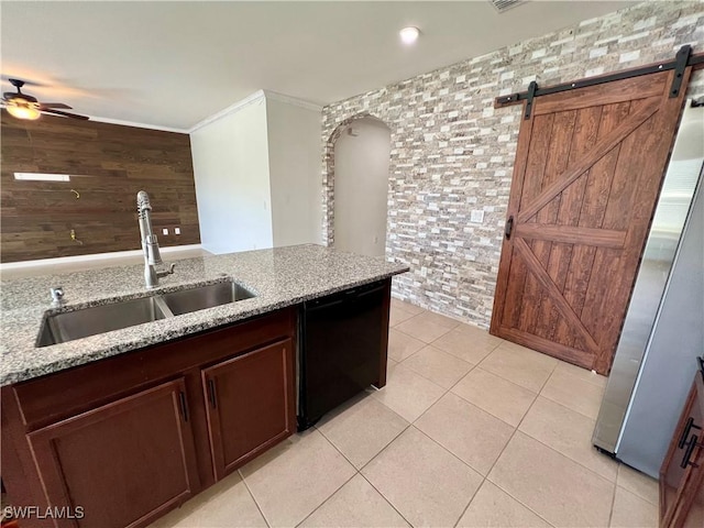 kitchen with stainless steel refrigerator, dishwasher, sink, light stone countertops, and a barn door