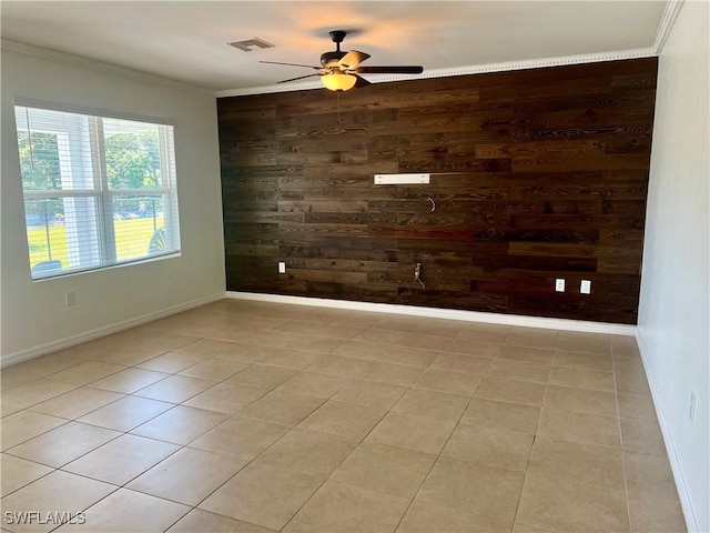 spare room featuring ceiling fan, ornamental molding, light tile patterned floors, and wood walls