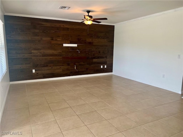 spare room with crown molding, light tile patterned flooring, ceiling fan, and wood walls