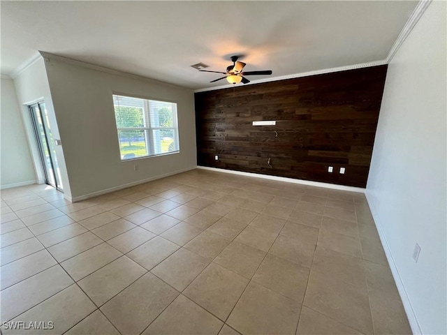 empty room featuring crown molding, light tile patterned flooring, ceiling fan, and wooden walls