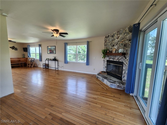373 Hile Ln, Punta Gorda, FL 33982 - unfurnished living room featuring hardwood / wood-style flooring, a ceiling fan, a stone fireplace, and baseboards
