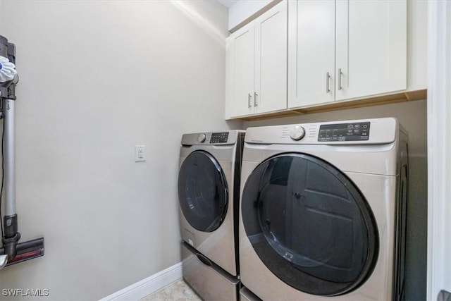 laundry area featuring washing machine and dryer, cabinet space, and baseboards