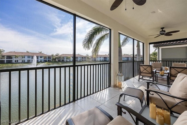 sunroom / solarium with ceiling fan, a water view, and a residential view