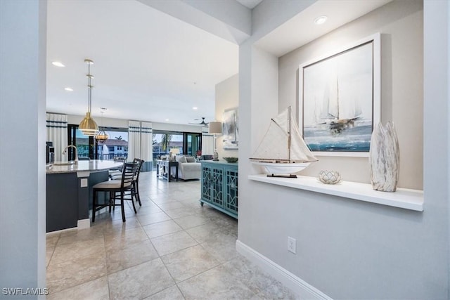 hall featuring baseboards, light tile patterned flooring, and recessed lighting