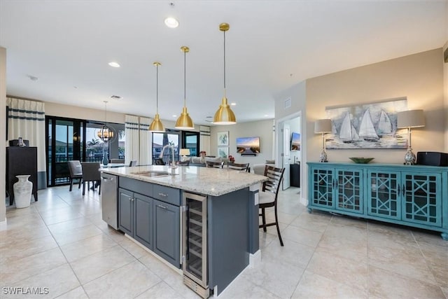 kitchen featuring hanging light fixtures, a kitchen island with sink, wine cooler, and a sink