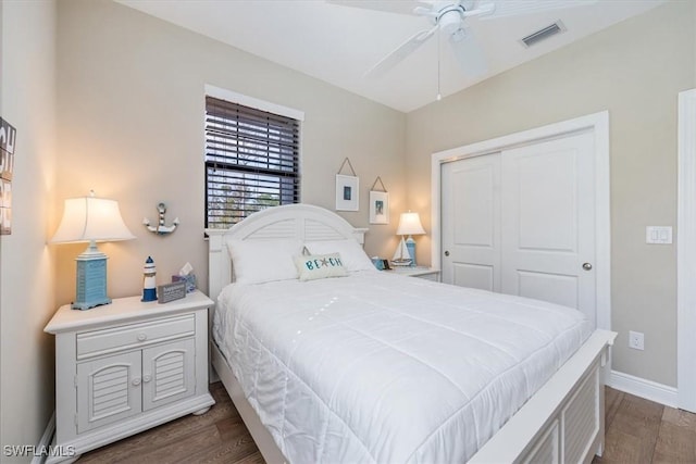 bedroom with dark wood-style flooring, a ceiling fan, visible vents, baseboards, and a closet