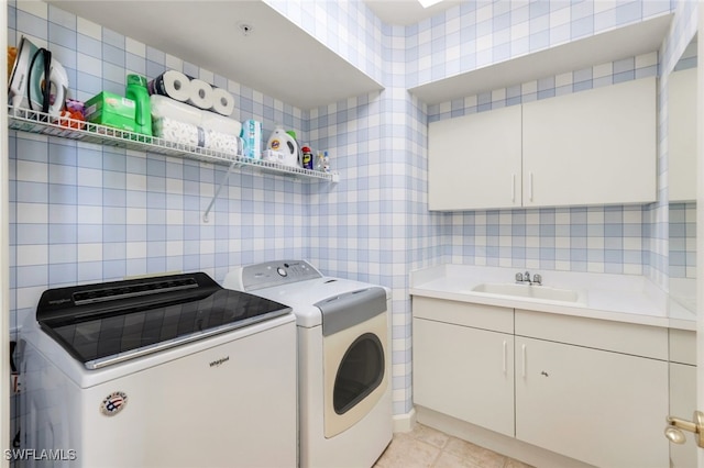 laundry area featuring washing machine and clothes dryer, sink, cabinets, and light tile patterned floors