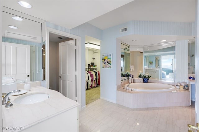 bathroom with vanity and a relaxing tiled tub