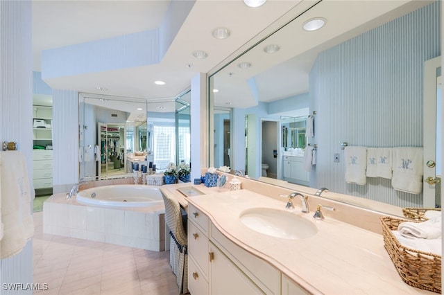 bathroom with tiled bath, tile patterned floors, vanity, and toilet