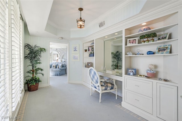 home office featuring built in desk, a raised ceiling, crown molding, light colored carpet, and built in features