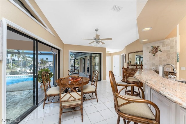 tiled dining space featuring sink, vaulted ceiling, and ceiling fan