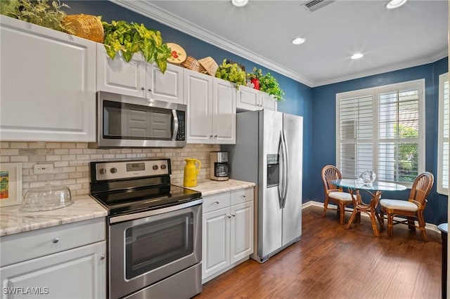 kitchen with stainless steel appliances, white cabinets, ornamental molding, and dark wood-style floors