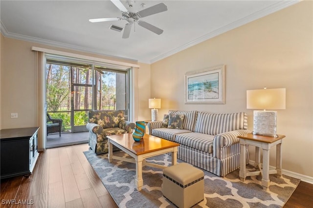 living room with ceiling fan, wood finished floors, visible vents, baseboards, and ornamental molding