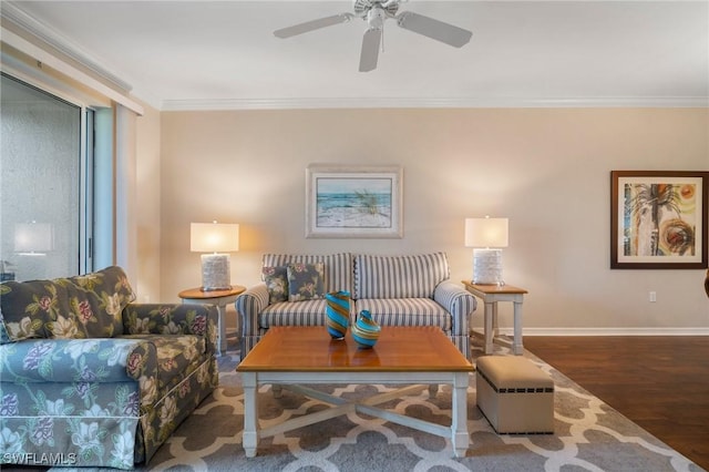 living area with baseboards, ceiling fan, wood finished floors, and crown molding