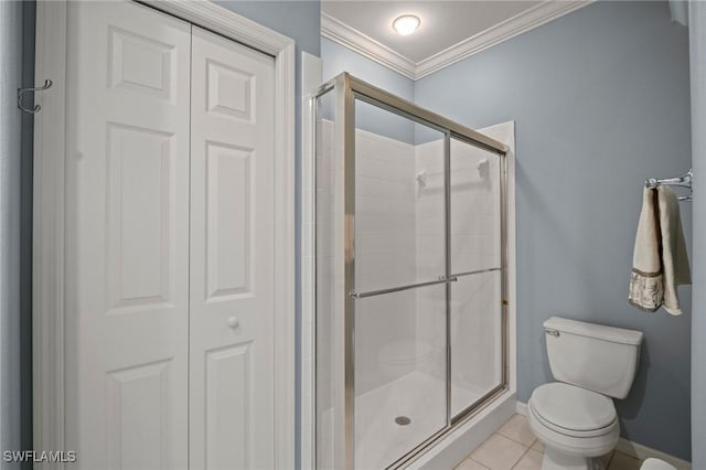 bathroom with tile patterned flooring, toilet, baseboards, a shower stall, and crown molding