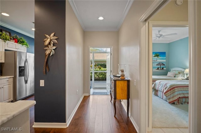 doorway featuring ornamental molding, dark wood-type flooring, baseboards, and a ceiling fan