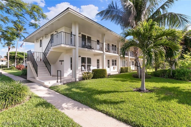 view of front of home featuring stairway, a front yard, and stucco siding