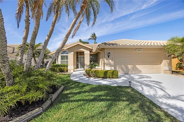 mediterranean / spanish house with a garage, a tiled roof, driveway, and stucco siding