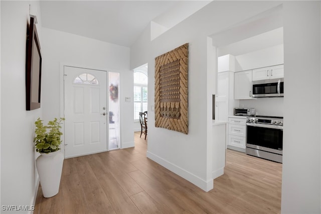 foyer featuring a toaster, light wood-type flooring, and baseboards