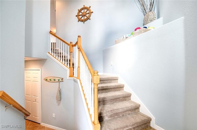 stairs with baseboards, a towering ceiling, and tile patterned floors