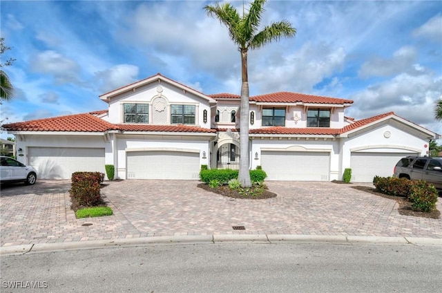 mediterranean / spanish-style home featuring decorative driveway, a tile roof, and stucco siding