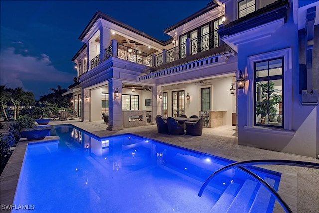 233 Mermaids Bight, Naples, FL 34103 - back of house at night with ceiling fan, a patio area, french doors, a balcony, and an outdoor pool