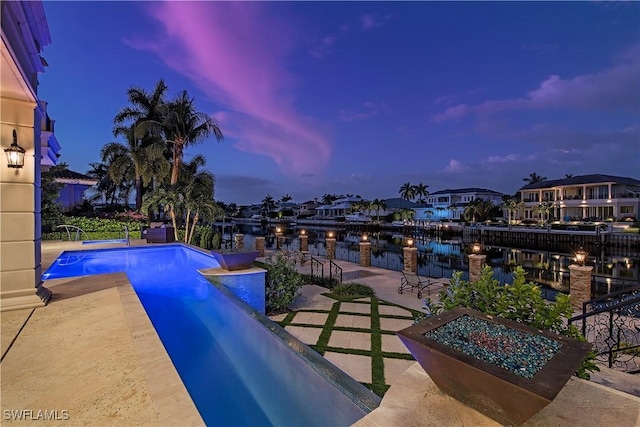 233 Mermaids Bight, Naples, FL 34103 - pool at dusk featuring a residential view, a patio, a water view, and an outdoor pool