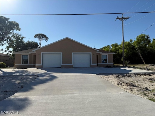 single story home featuring concrete driveway, an attached garage, and stucco siding